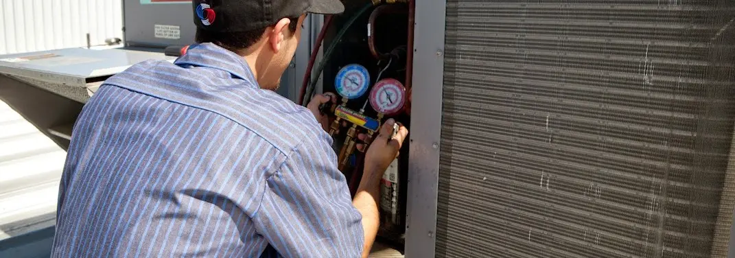 HVAC technician servicing a condenser unit in Pekin
