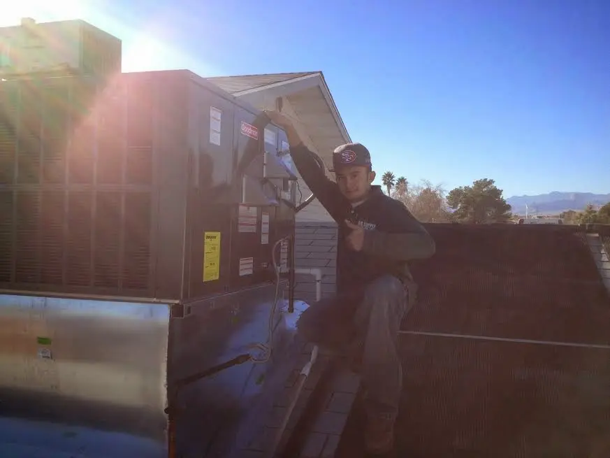 HVAC technician performing Air Duct Cleaning on a rooftop unit in Pekin